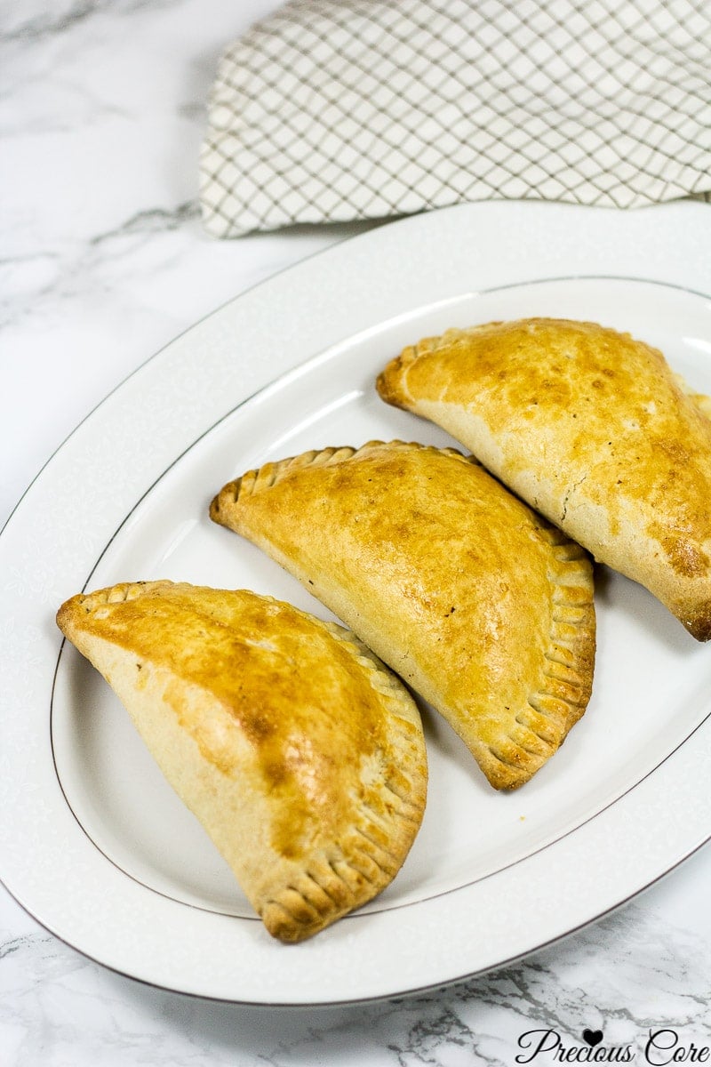 3 African meat pies on a white platter.