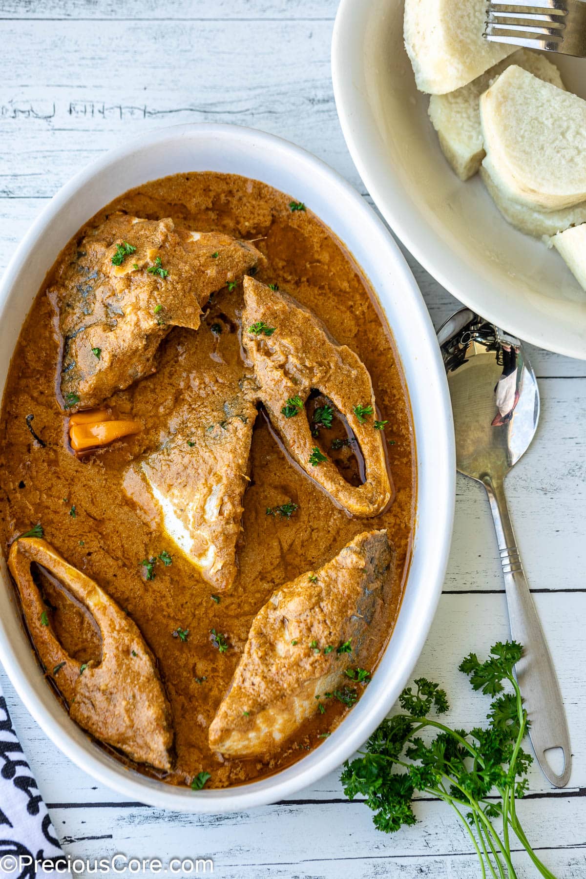 Njangsa sauce in a white oval bowl with white yams on the side.