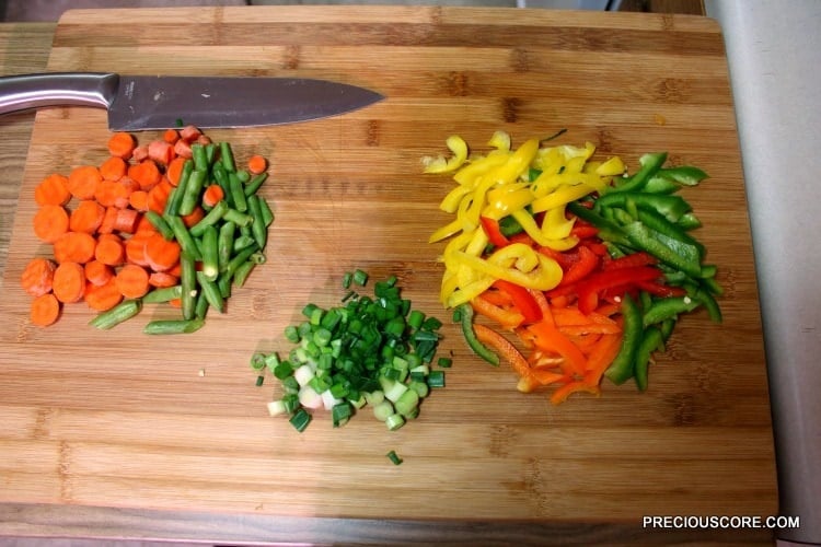 Colorful chopped vegetables on a wooden cutting board.