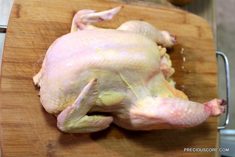 Whole chicken on a wooden cutting board.