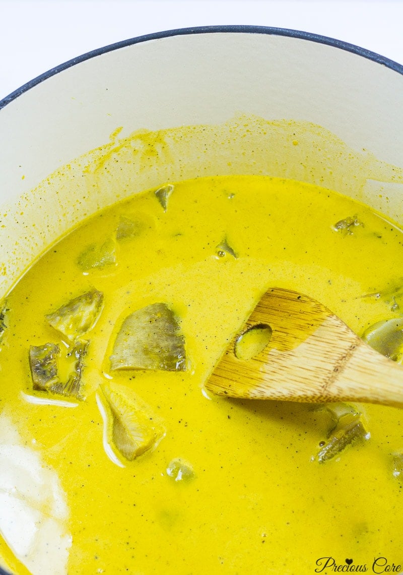 Spatula in a pot of bright yellow Achu Soup.
