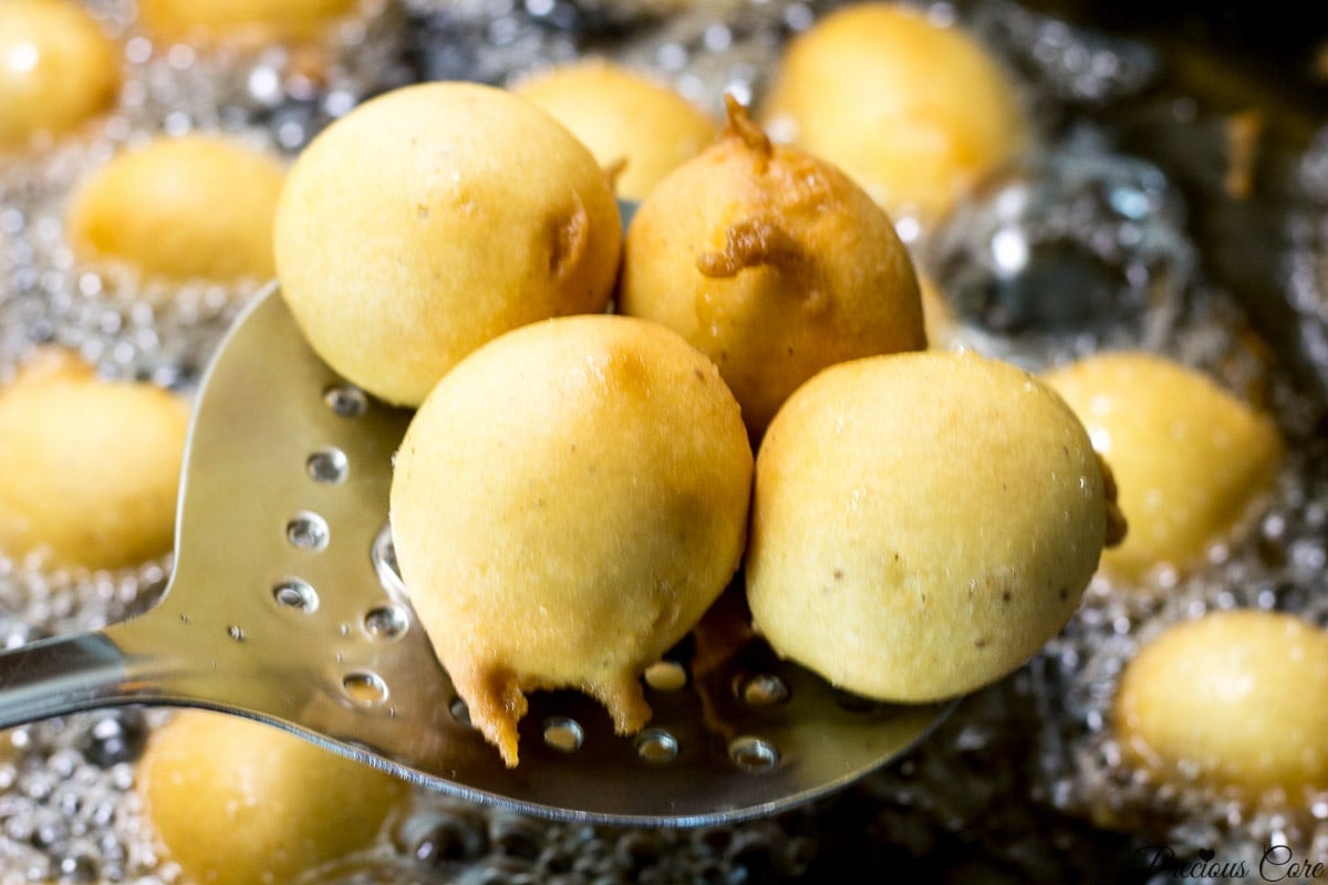 Frying spoon lifting some Cameroon doughnuts.