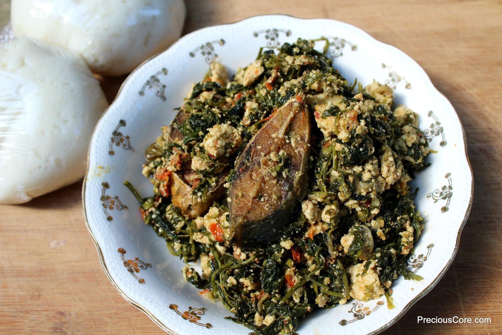 A bowl of Njama Njama with Egusi topped with fried fish.