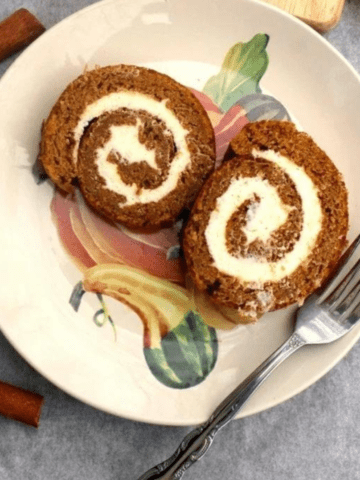 Two slices of pumpkin roll cake on a plate with a fork.