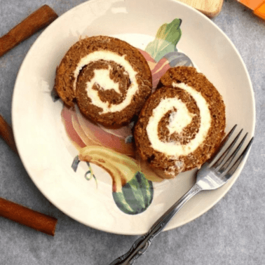 Two slices of pumpkin roll cake on a plate with a fork.