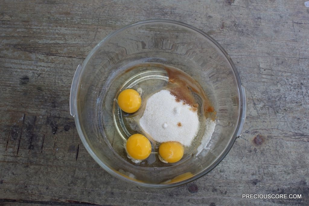 Eggs, sugar, and vanilla in a glass mixing bowl.