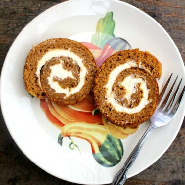 Two slices of pumpkin roll cake on a plate with a fork.