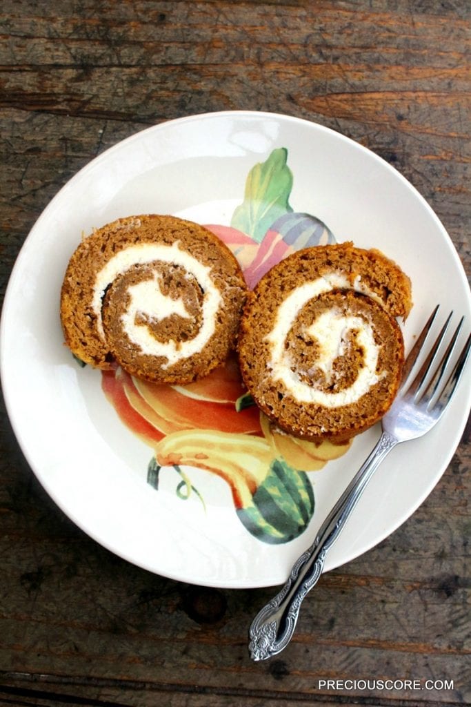 Two slices of pumpkin roll cake on a plate with a fork.