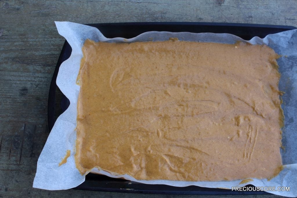 Pumpkin roll cake batter in a lined pan.