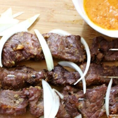 Cameroonian soya on a cutting board with onions.