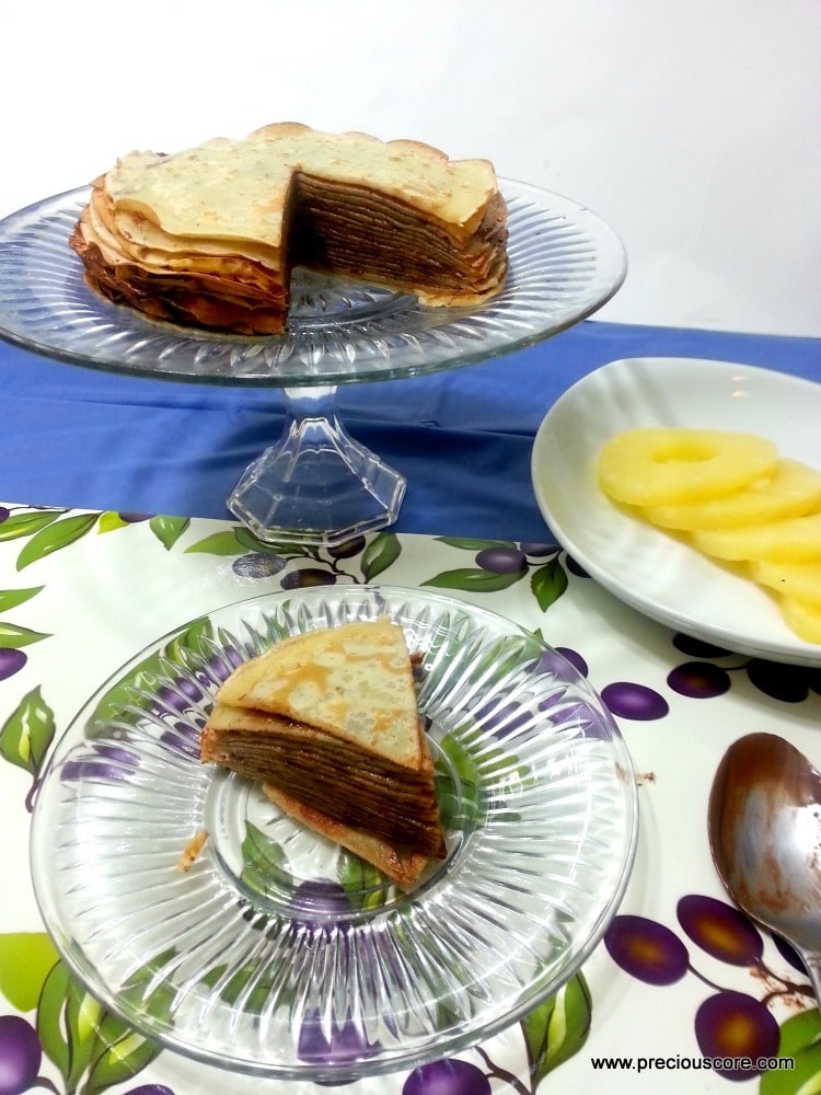 Crepe chocolate cake with one slice removed onto a plate.