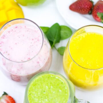 Three differently-colored smoothies in small glasses.