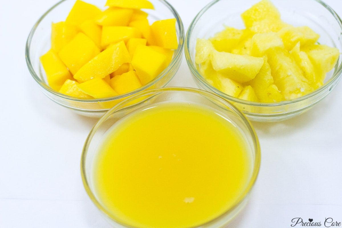 Bowls of pineapple, mango, and orange juice.