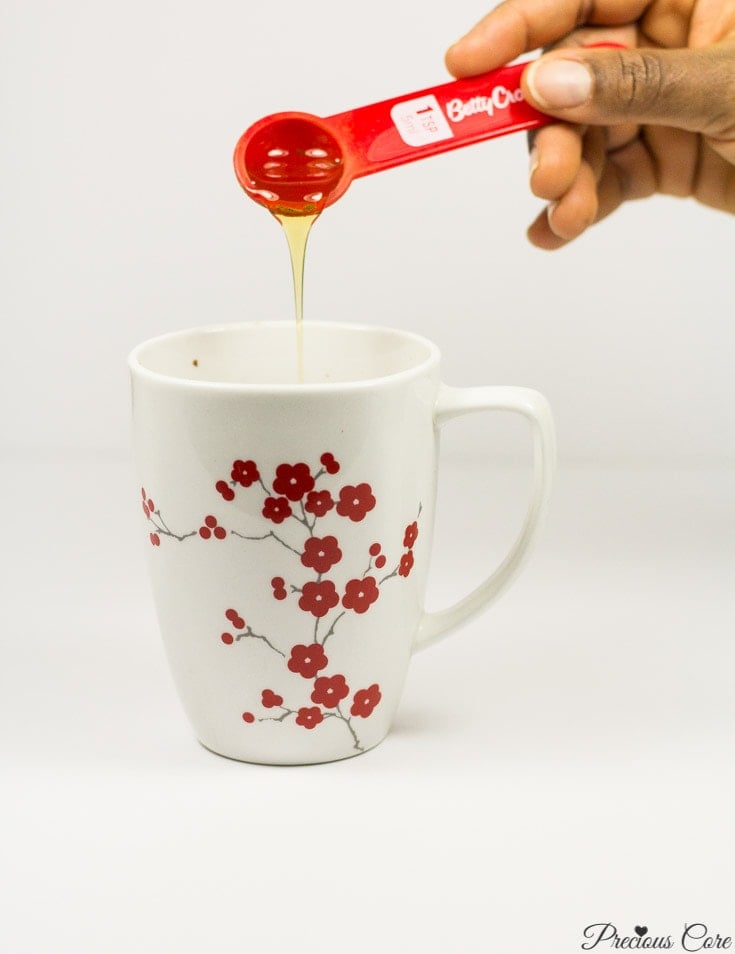 Honey pouring into a floral mug.