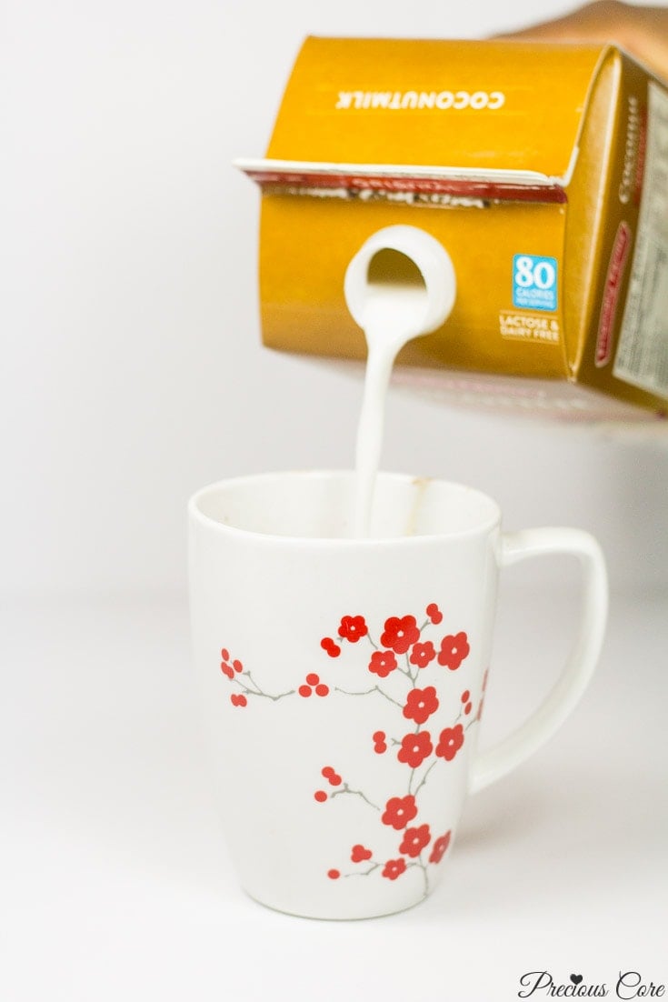 Carton pouring coconut milk into a floral mug.