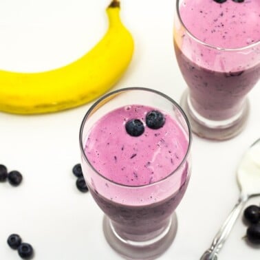 Two tall glasses of purple smoothie.