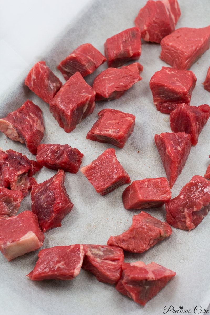 Cubed beef on a lined baking sheet.