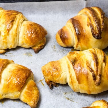 Homemade croissants on parchment paper.