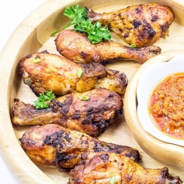 Grilled chicken drumsticks in a wooden serving dish.