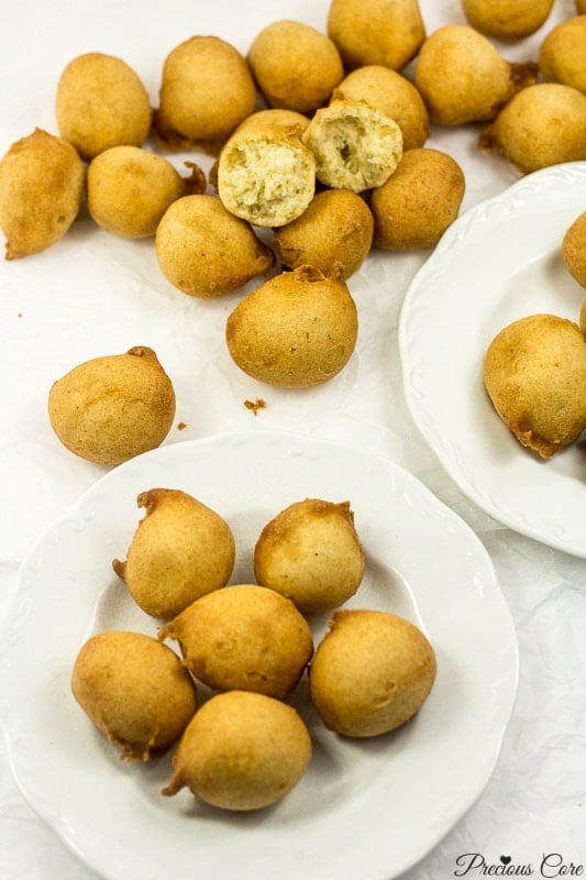 Cameroon doughnuts on two white plates and parchment paper.