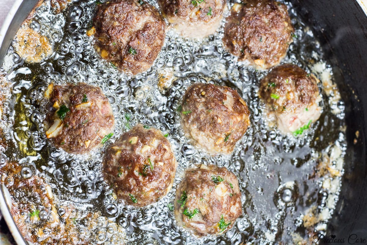 Meatballs frying in a pan.