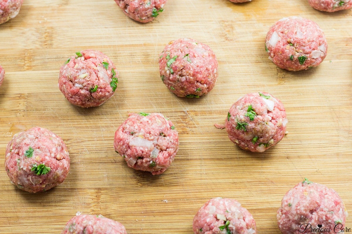 Raw meatballs on a wooden cutting board.