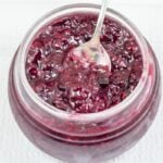 Spoon in a jar of mixed berry jam.