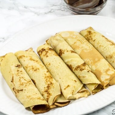 Cameroonian pancakes rolled on a white plate.