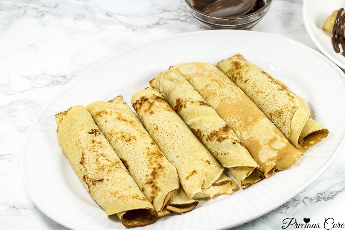 Cameroonian pancakes rolled on a white plate.