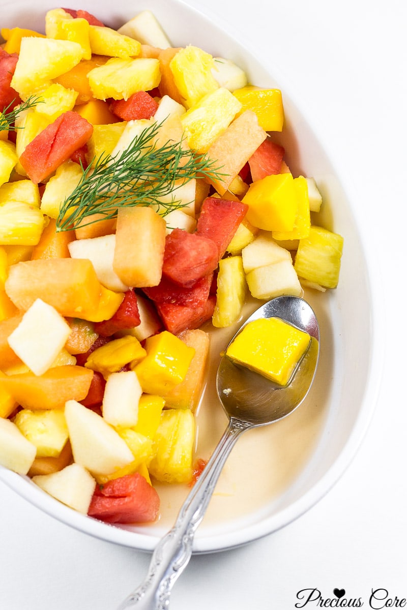 Spoon scooping fruit salad from a serving bowl.