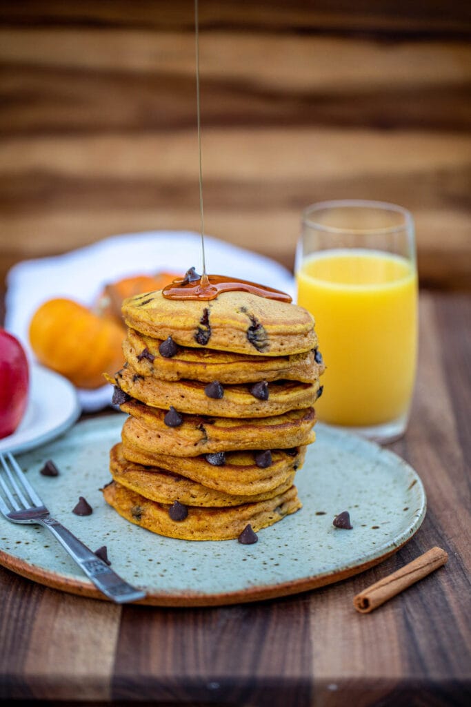 Stack of pancakes with honey drizzling on top.