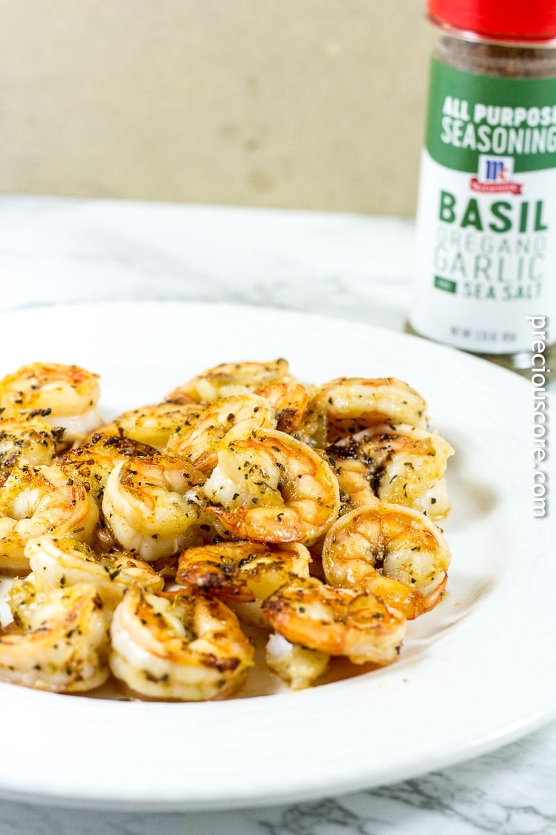 Shrimp pasta on a plate near a container of all-purpose seasoning.