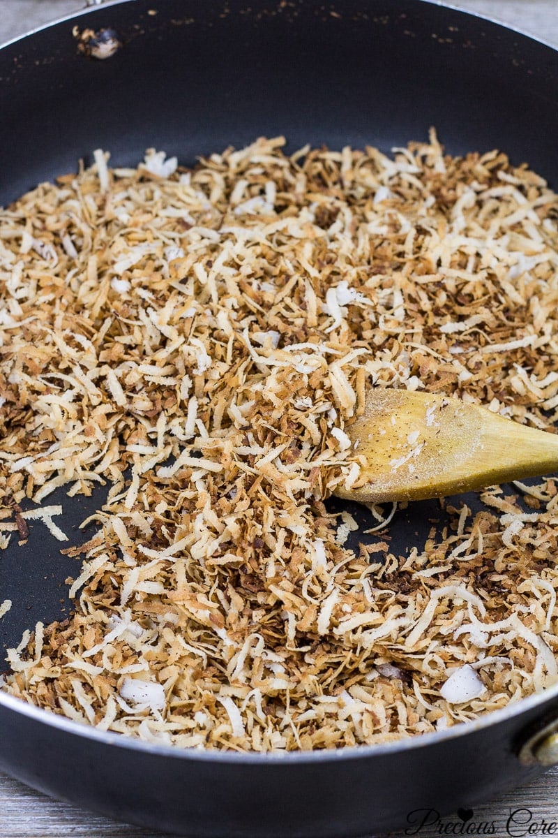 Spoon stirring coconut flakes.