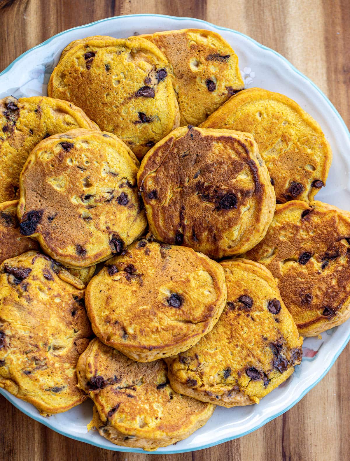 A round tray with loads of pancakes with chocolate chips.