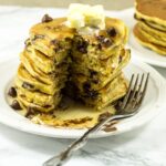 A stack of pumpkin chocolate chip pancakes with maple syrup and chocolate chips. The perfect fall breakfast recipe.