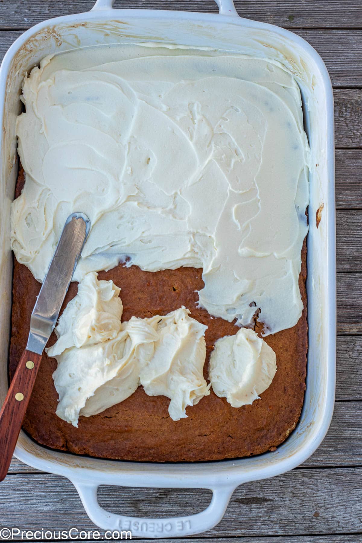 Spreading cream cheese frosting on pumpkin cake.