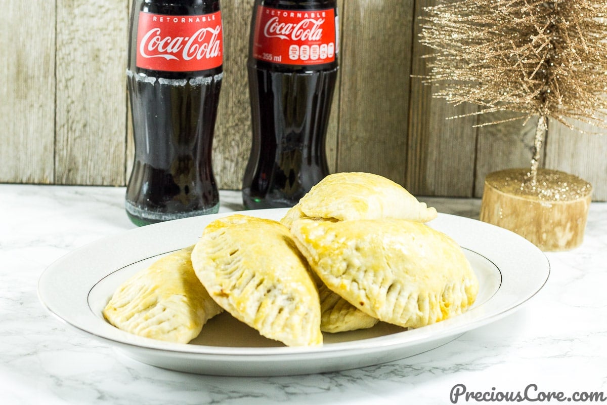 Chicken pies on a plate with bottles of Coca-Cola.