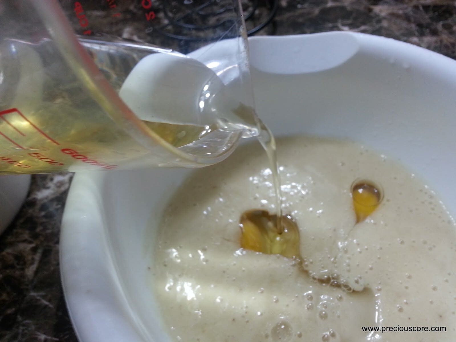 Vegetable oil pouring into a mixing bowl.