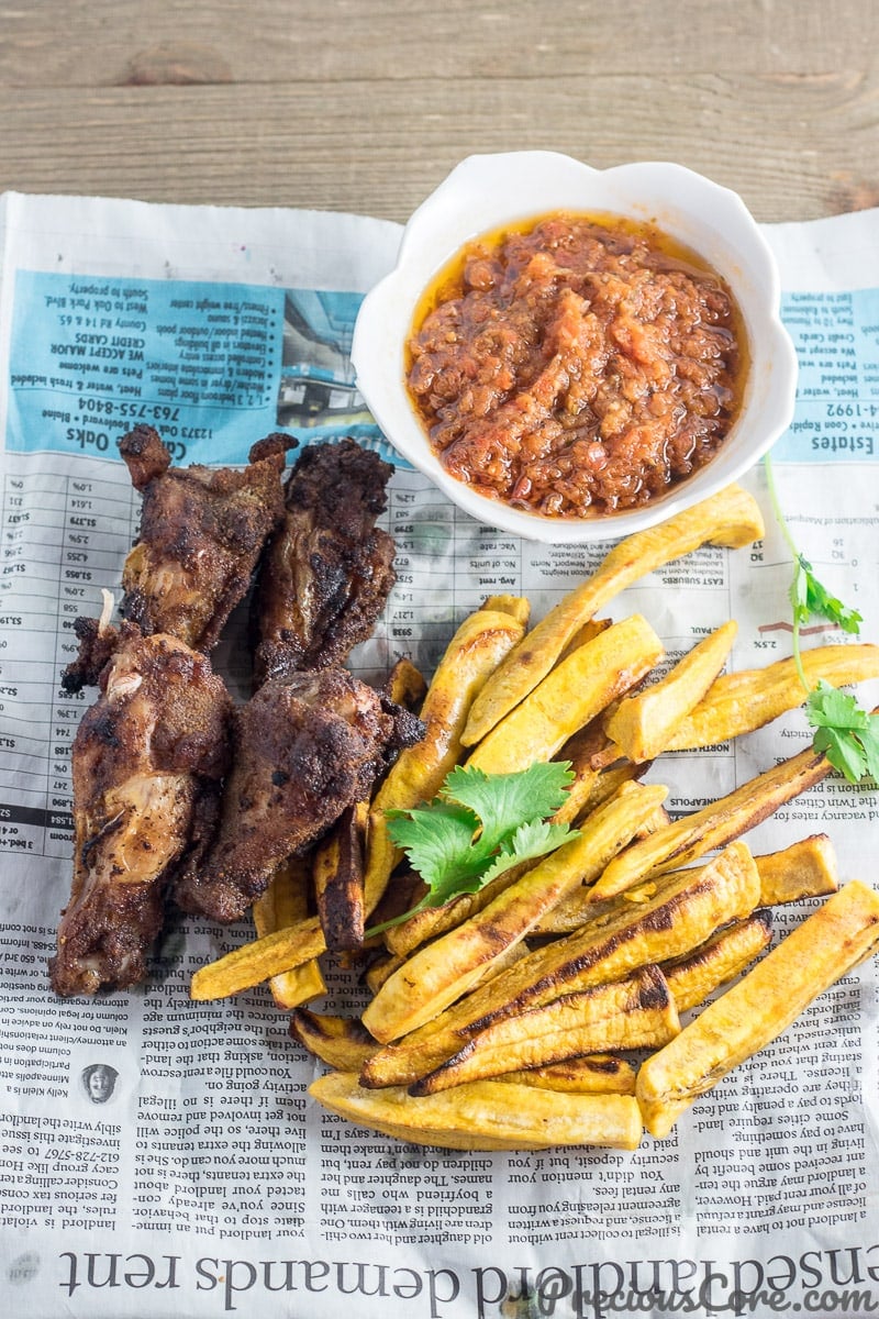 Plantains and wings on serving paper.