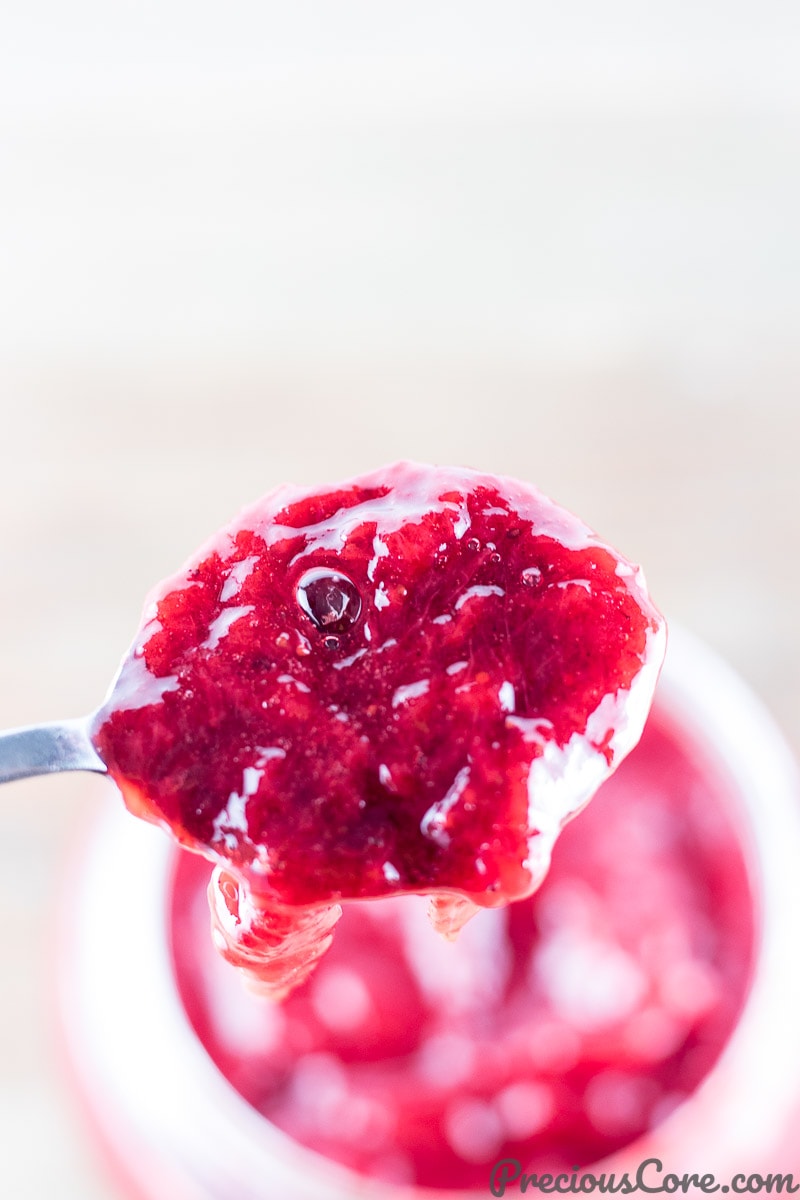 Spoon scooping strawberry jam.