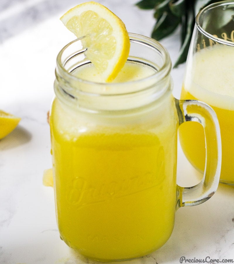 A mason jar of pineapple ginger juice decorated with a half moon lemon slice.