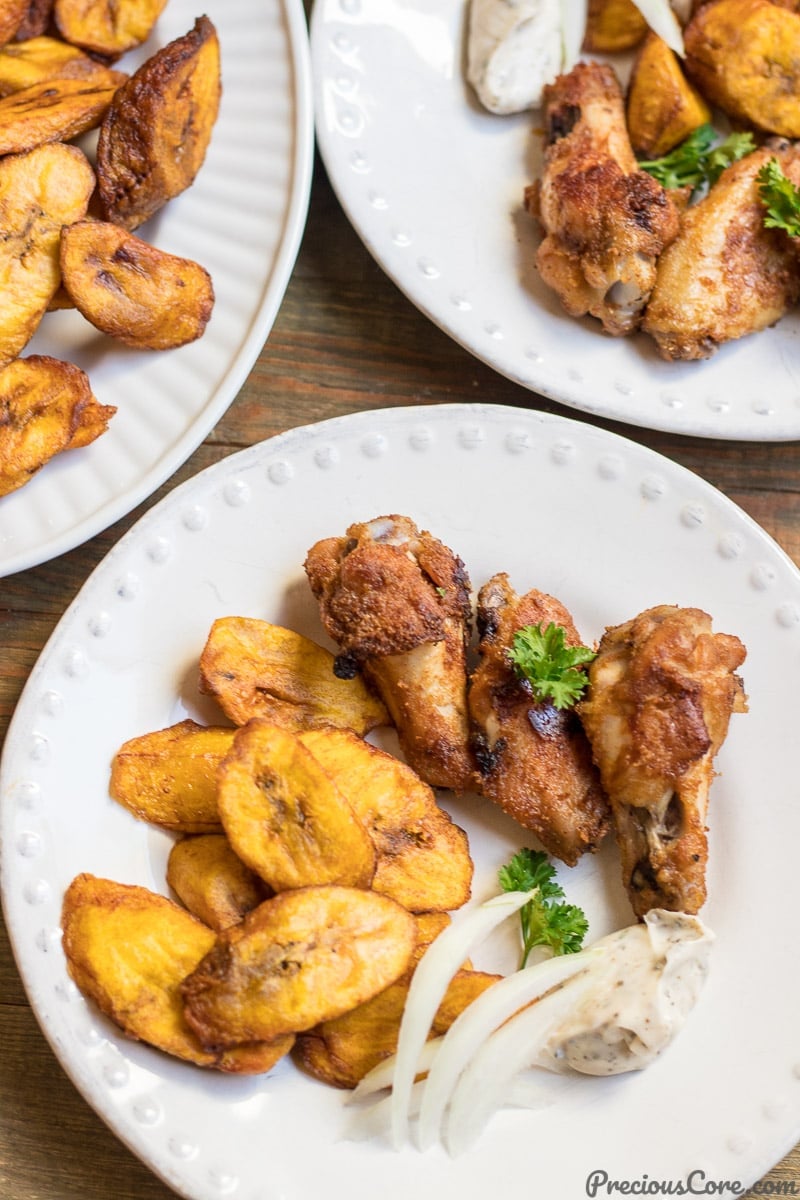 Sweet fried plantains on a white plate with oven grilled chicken wings.