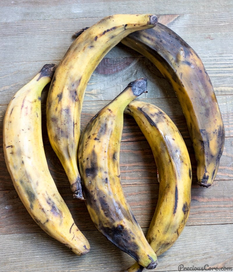 5 yellow ripe plantains on a wooden board.