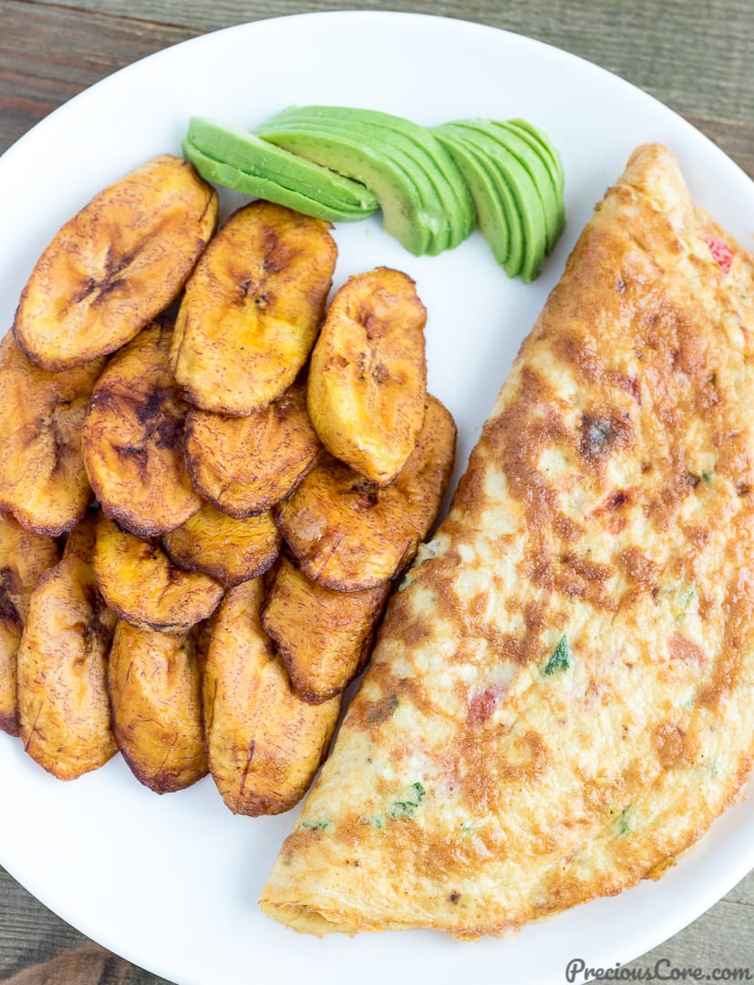 Fried plantains on a plate with an omelet and avocado.