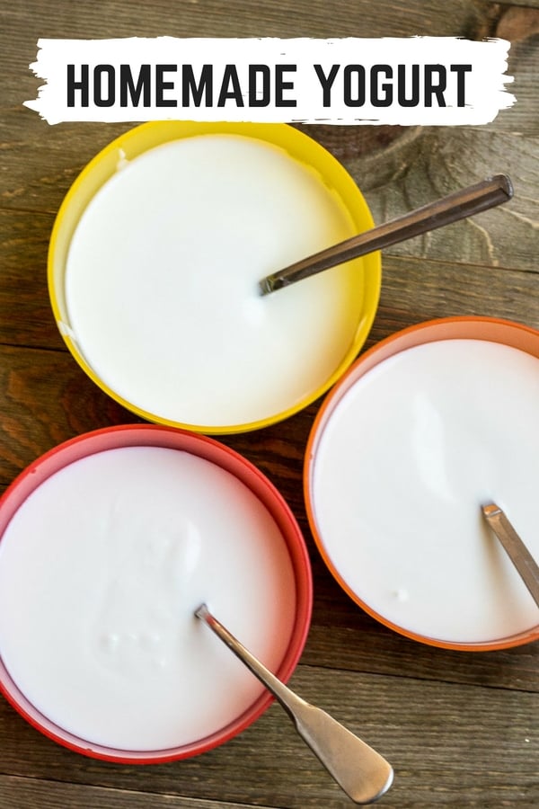 Three bowls of yogurt with spoons.