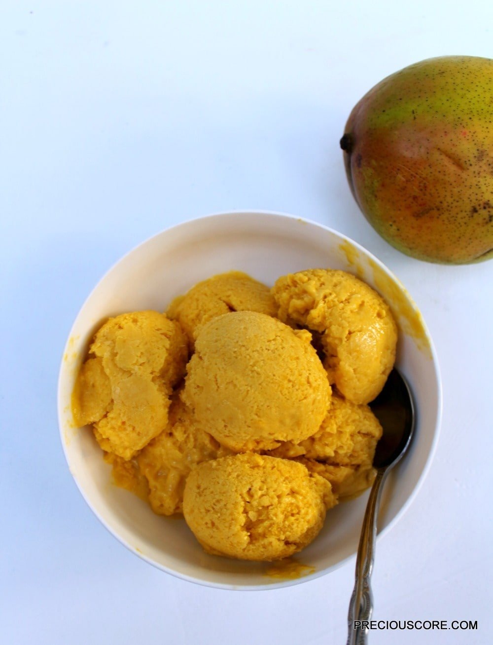 Spoon in a bowl of mango coconut sorbet.