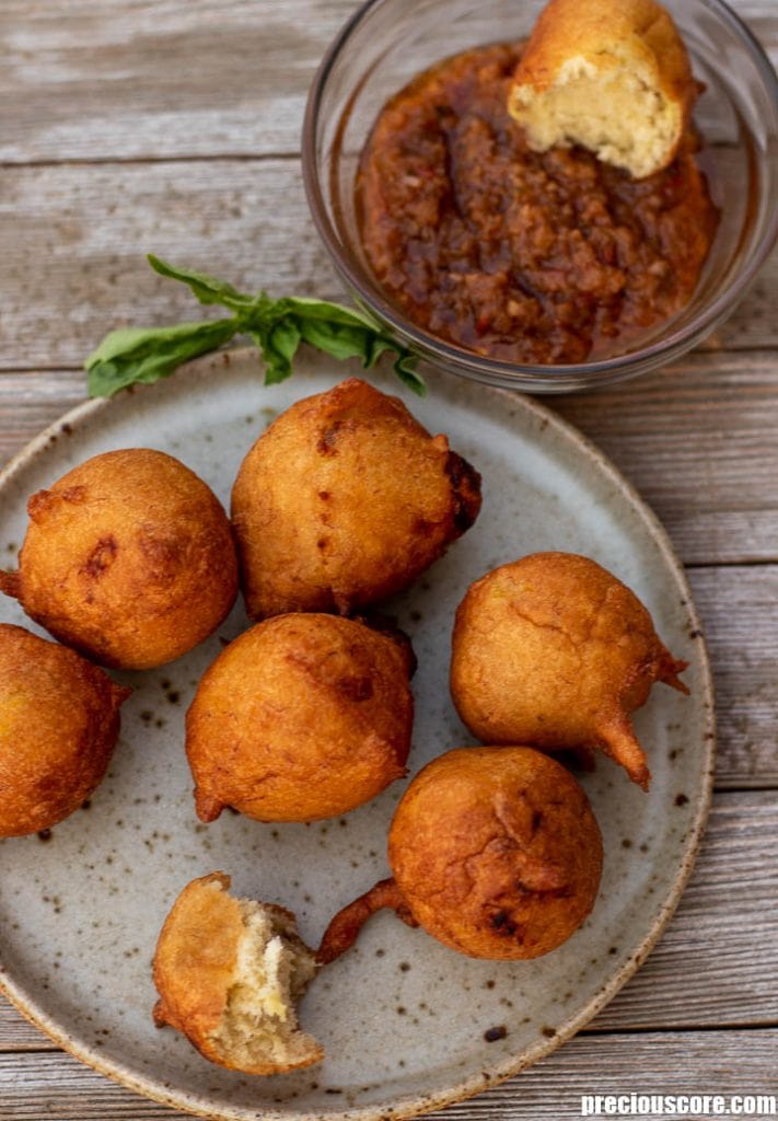 Banana Fritters on a plate, a bowl of pepper sauce on the side