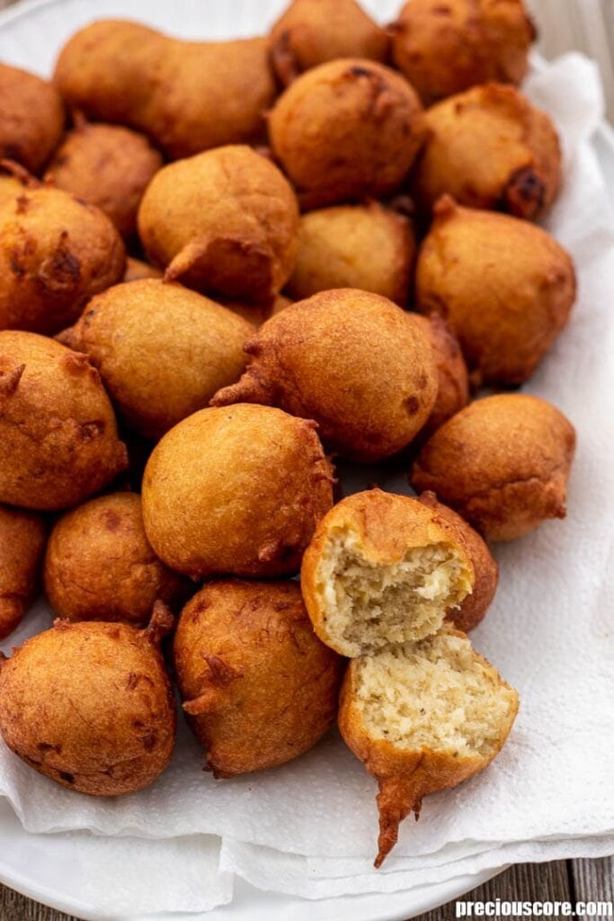 Banana fritters on a platter with one opened up to show texture