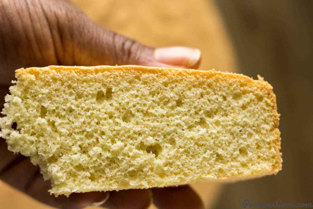 Person holding a slice of vanilla sponge cake.