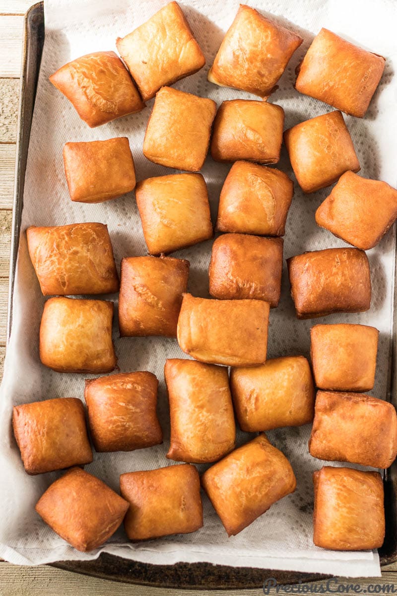 Cooked Beignets on a lined baking sheet.